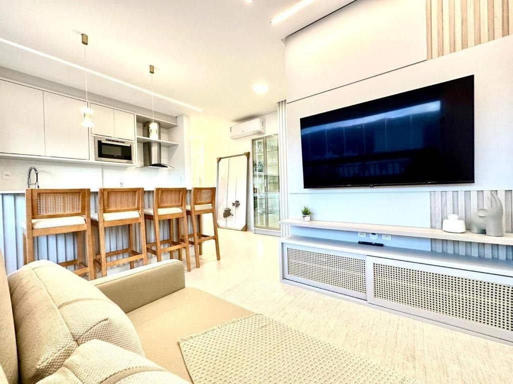 B258 - Apto de luxo com vista mar em Bombinhas في بومباس: غرفة معيشة مع تلفزيون بشاشة مسطحة كبيرة على جدار