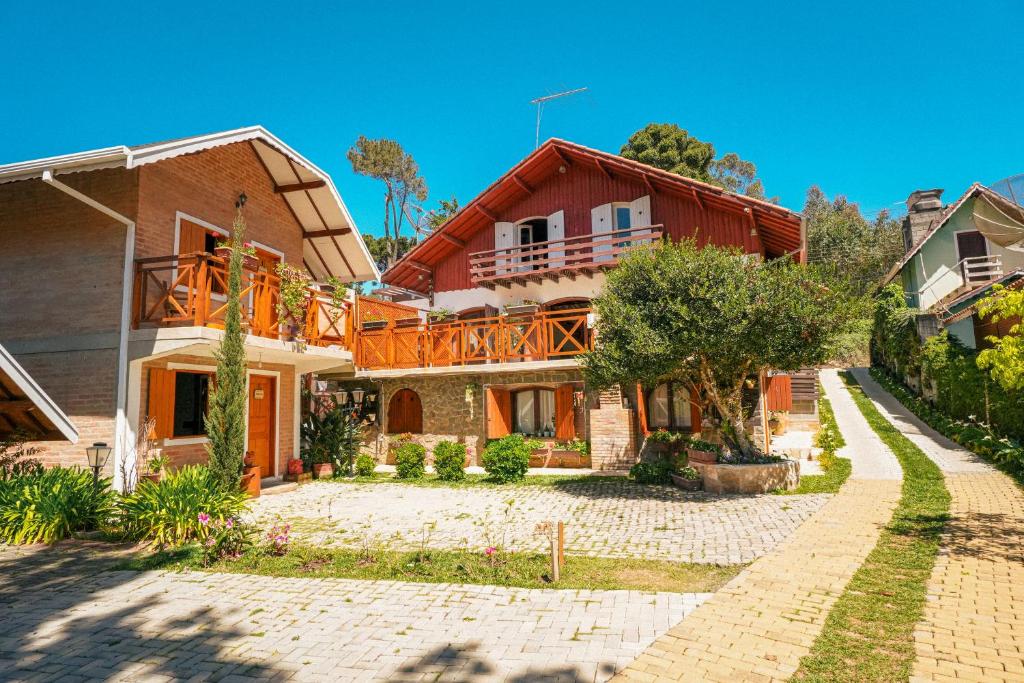 uma casa grande com uma varanda numa rua em VELINN Pousadas Flor da Montanha em Monte Verde