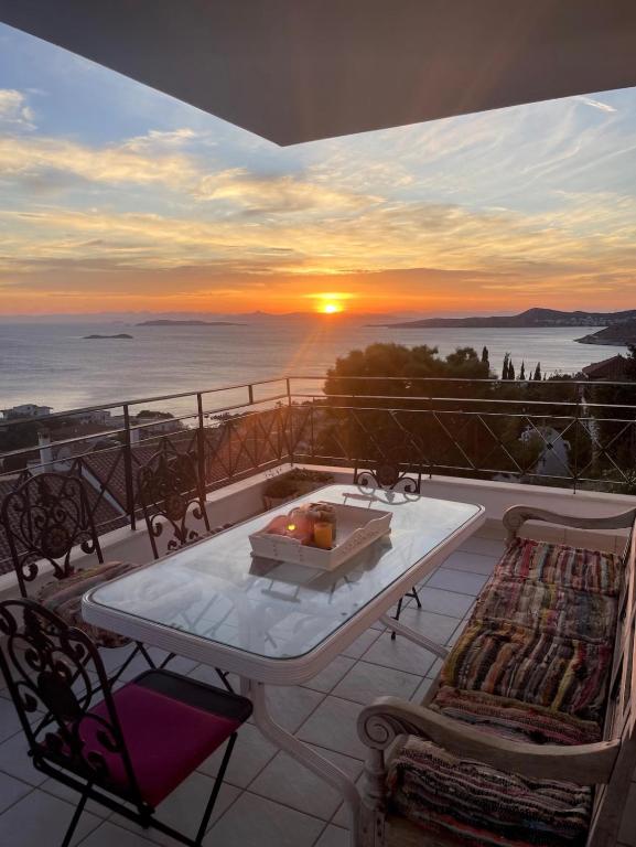 a table and chairs on a balcony with the sunset at Art Blue Residence - Panorama Maisonette in Aghia Marina