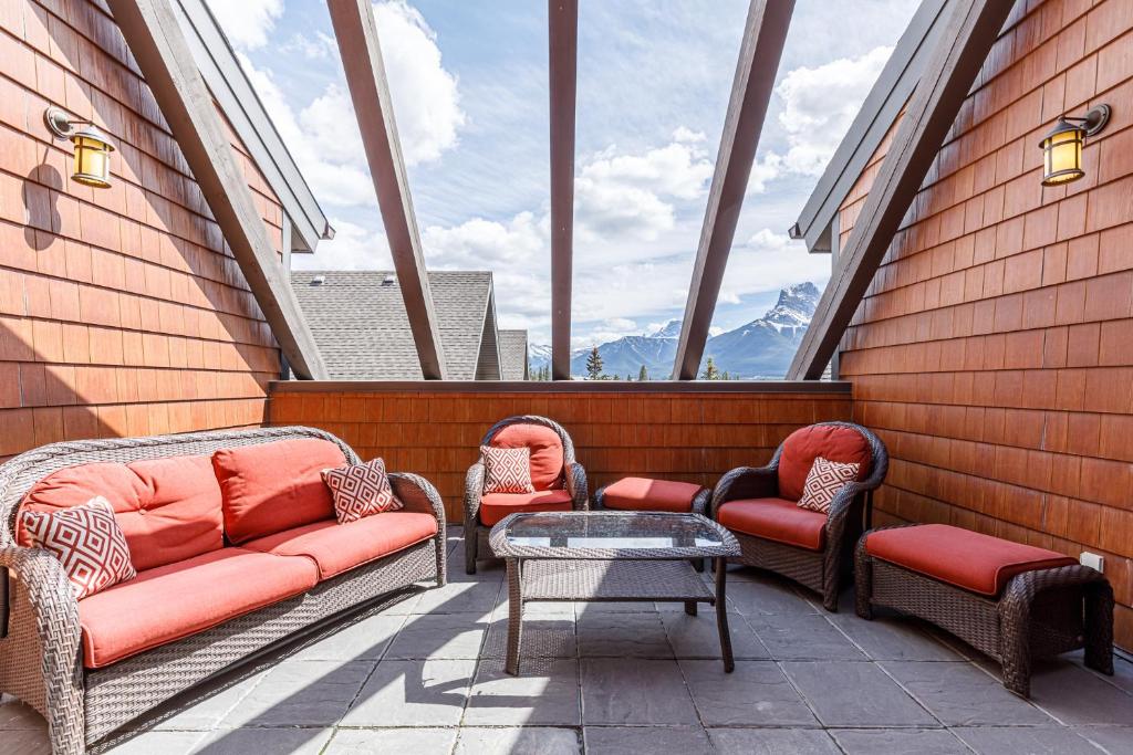 balcone con 3 sedie e tavolo di fronte alle finestre di Rocky Mountain High at Grande Rockies Resort a Canmore