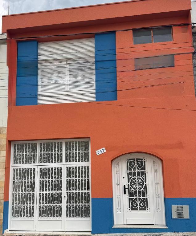 a orange and blue building with a white door at Pousada Sete Colinas in Bragança Paulista