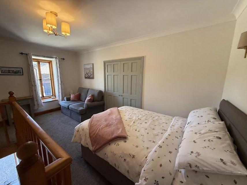 een slaapkamer met een bed en een bank bij The Cottage in Borrowdale Valley