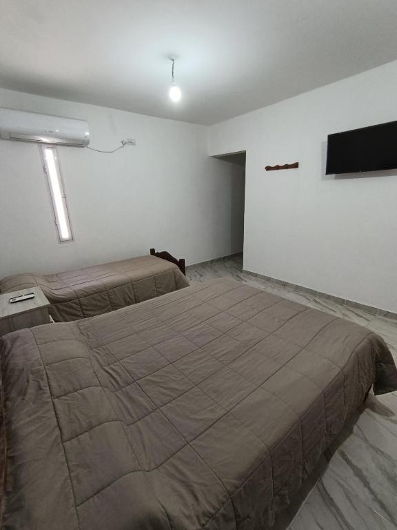 a bedroom with two beds and a flat screen tv at La finca in Fiambalá