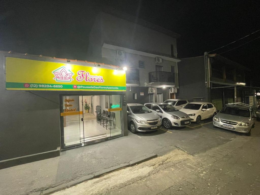 a group of cars parked in a parking lot at night at Pousada das Flores in Aparecida