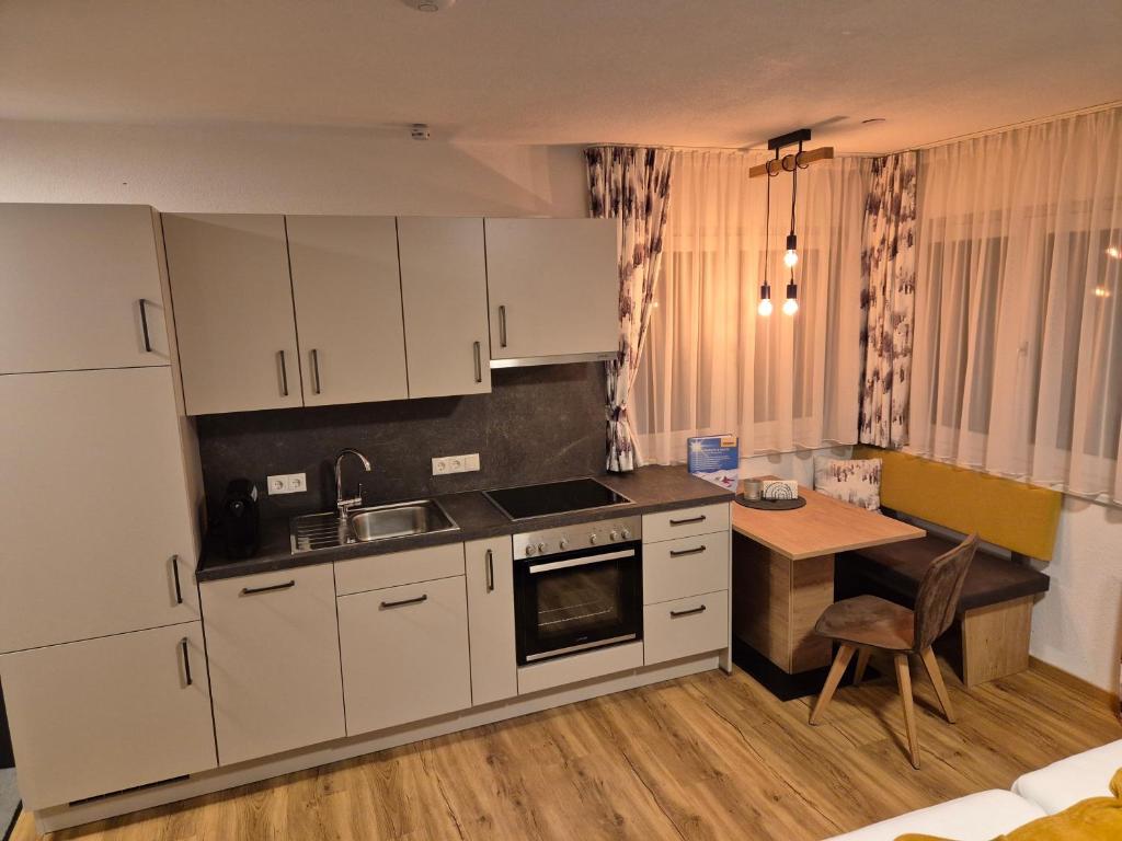 eine Küche mit weißen Schränken und einem Tisch darin in der Unterkunft Mountain alpine in Kappl