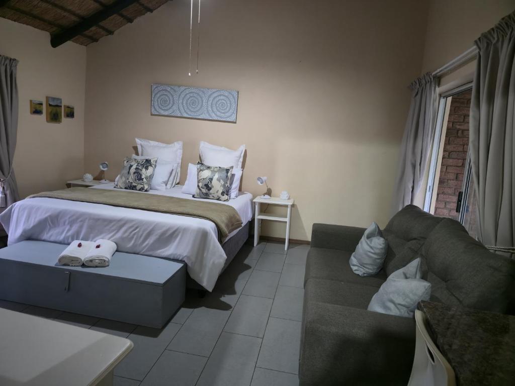 a bedroom with a large bed and a couch at Loubad Guest Farm in Modimolle