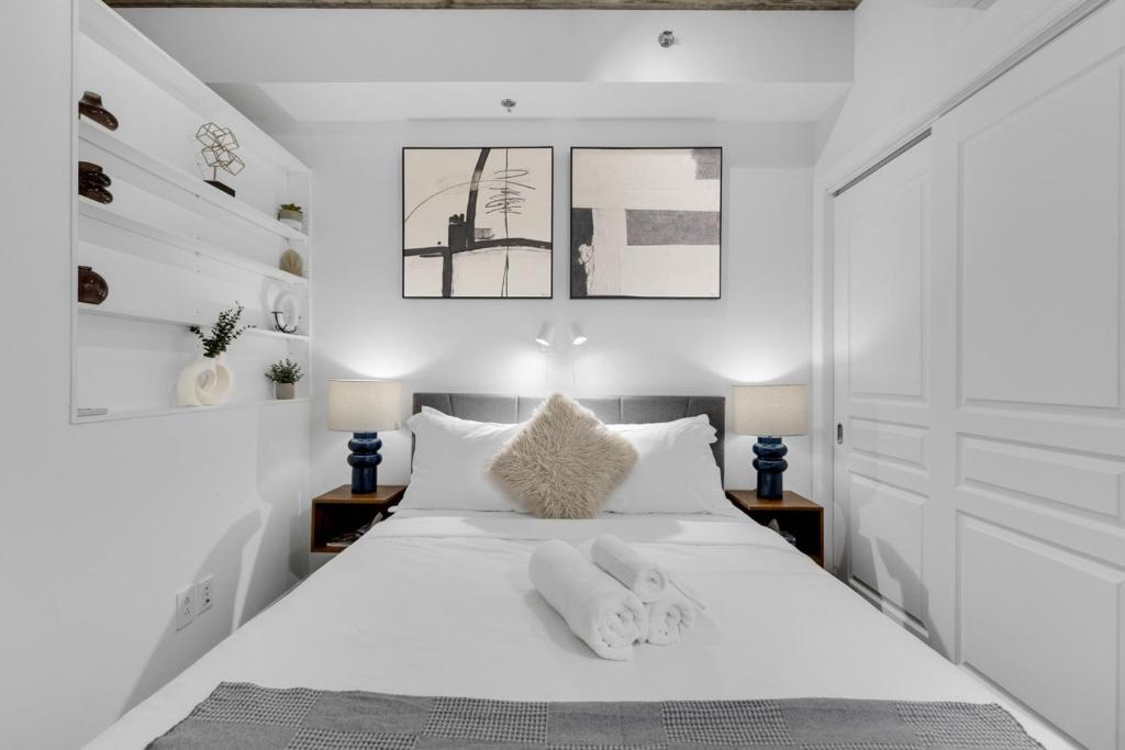 Un dormitorio con una cama blanca con dos animales de peluche. en Flat at the Foot of the Mountain With Parking, en Montreal