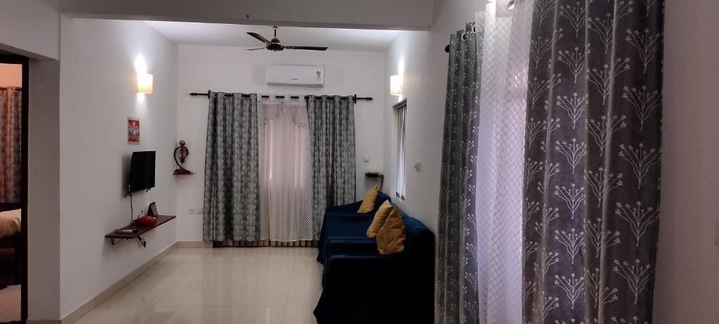 GTA&H BY Shan في كاندوليم: غرفة معيشة مع أريكة زرقاء والستائر