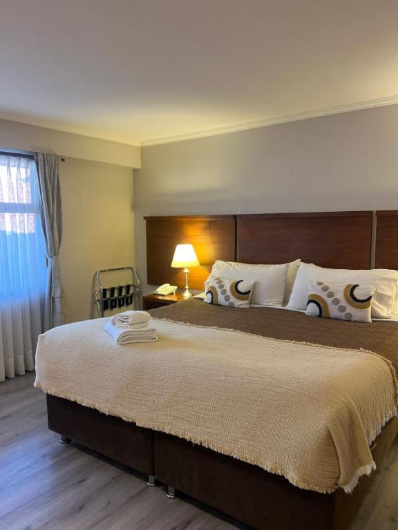 a bedroom with a large bed with a lamp and a chair at Hotel D&V Concepción in Concepción