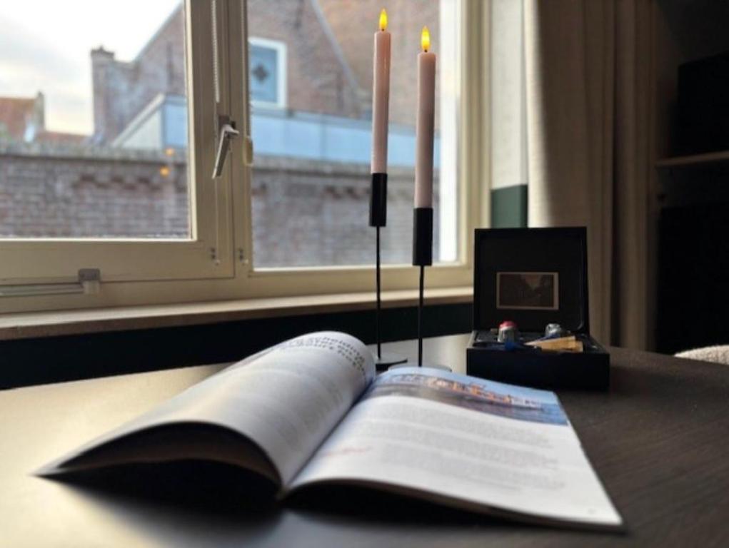 Ein offenes Buch liegt auf einem Tisch mit zwei Kerzen. in der Unterkunft B&B In de Kathoek in Blokzijl
