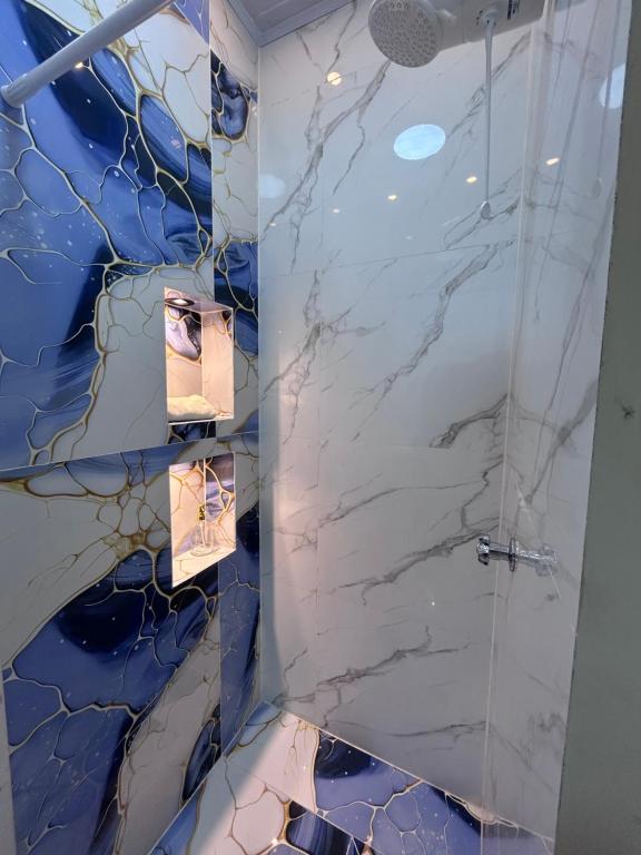 un bagno con doccia in marmo blu e bianco di Deramai a Santo Domingo de los Colorados