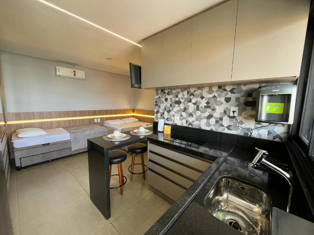 a small kitchen with a sink and a bed at Haven Residence in Uberlândia