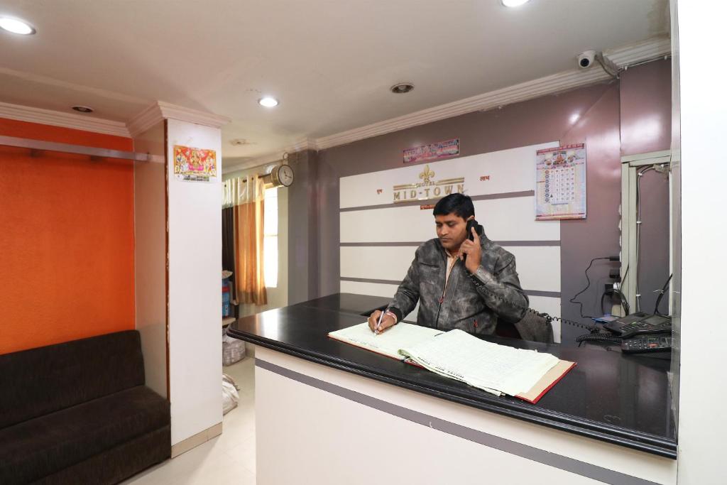 a man talking on a cell phone at a counter at Hotel O Midtown in Bhopal