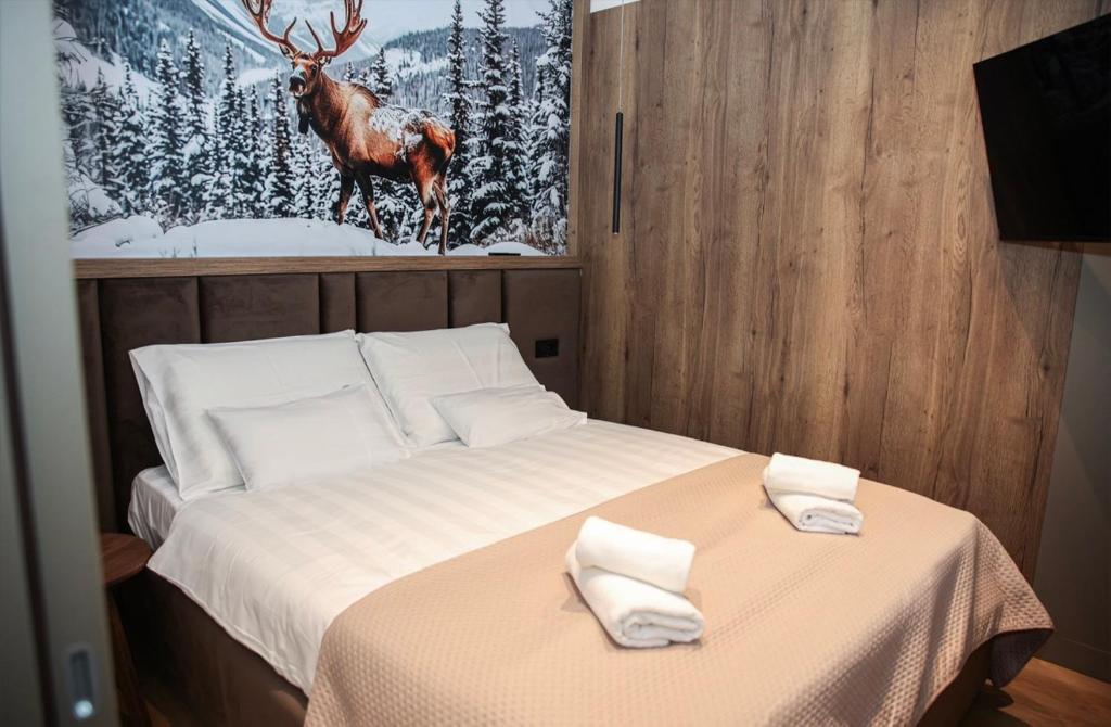 亚霍里纳Apartmani Ambar的卧室里有一张床，墙上挂着一只鹿