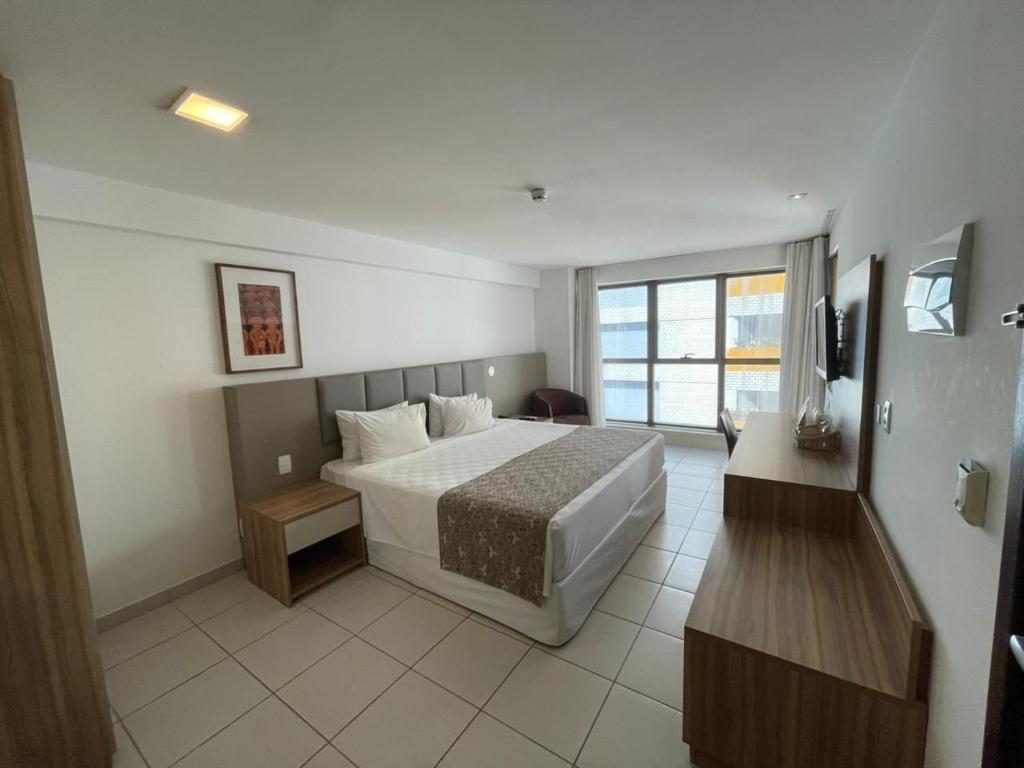 ein Hotelzimmer mit einem Bett und einem Fernseher in der Unterkunft Beach Class Executive por Yolo in Recife