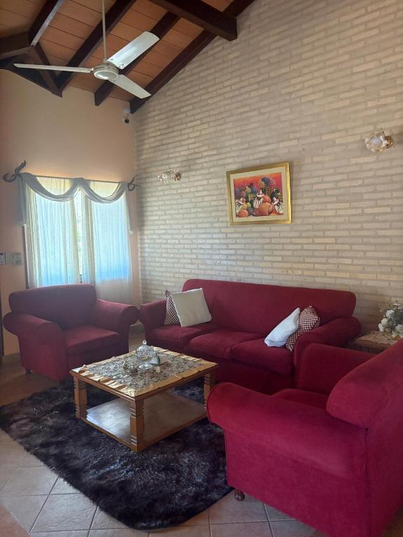Una sala de estar con un sofá rojo y una mesa de café. en Casa jardin, en Luque