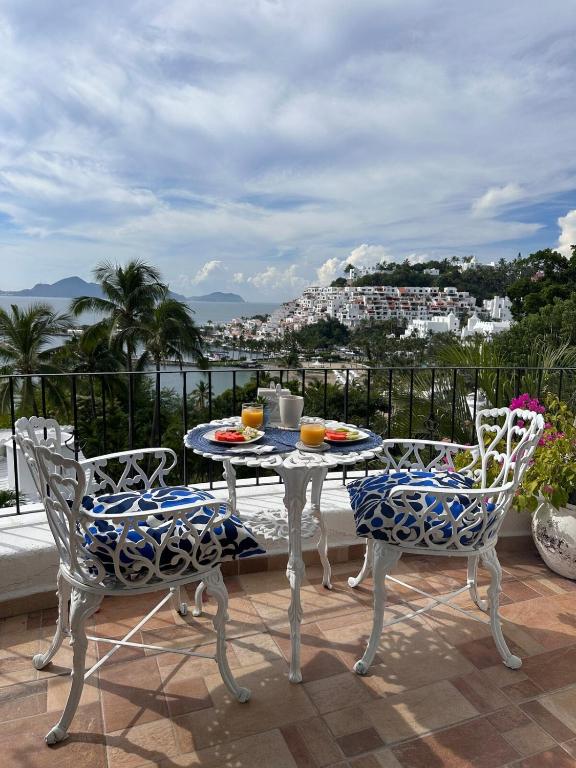 a table and chairs on a balcony with a view at Santorini, loft frente al mar in Manzanillo