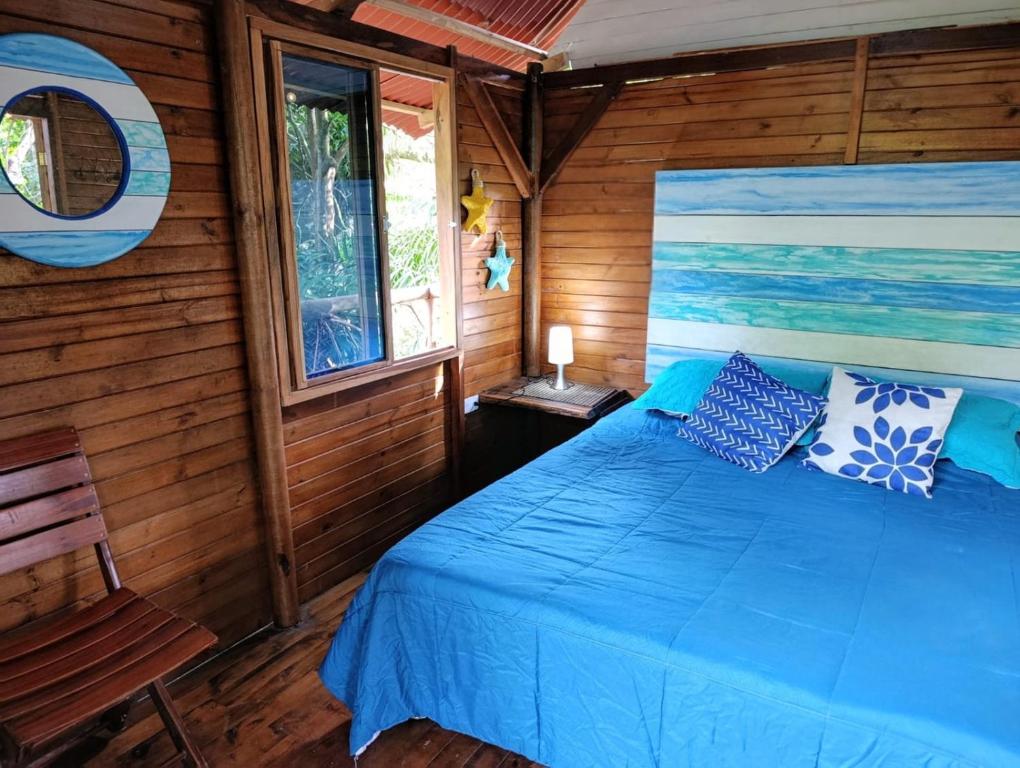 a bedroom with a blue bed in a wooden room at Excelsum Tayrona Garden Hotel in Calabazo