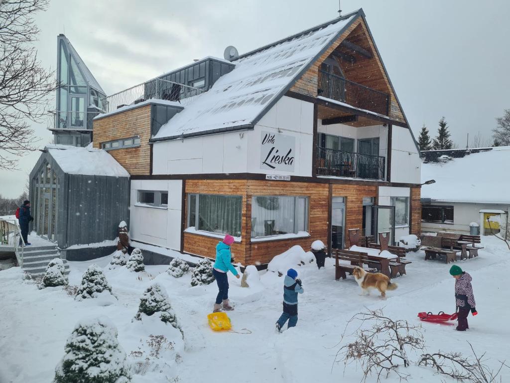 a group of people playing in the snow in front of a house at Boutique Hotel Vila Lieska in Smokovce