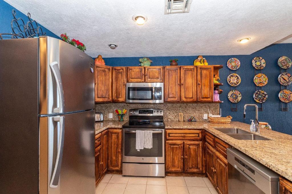 een keuken met houten kasten en een roestvrijstalen koelkast bij Sonoran Spa W409 in Campo del Medio