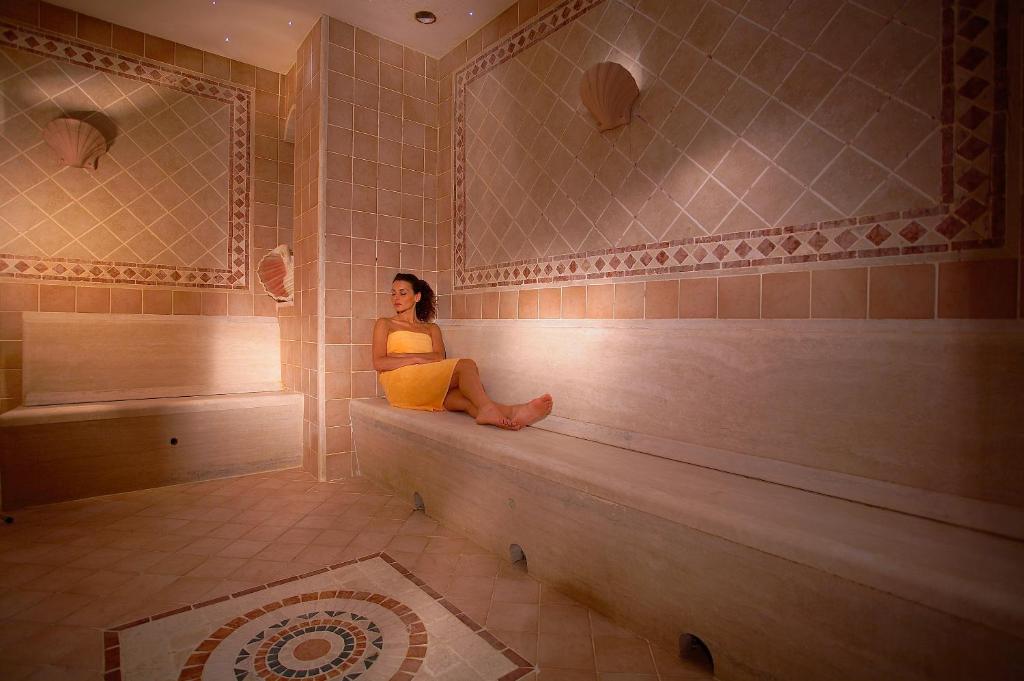 a woman sitting on a bench in a tub at Hotel Caparena in Taormina