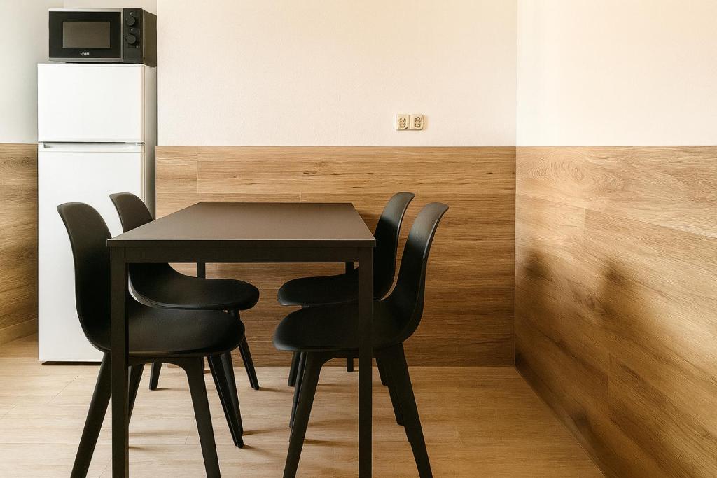 a black table and chairs in a room with a refrigerator at Monteurzimmer24-Leuna in Leuna