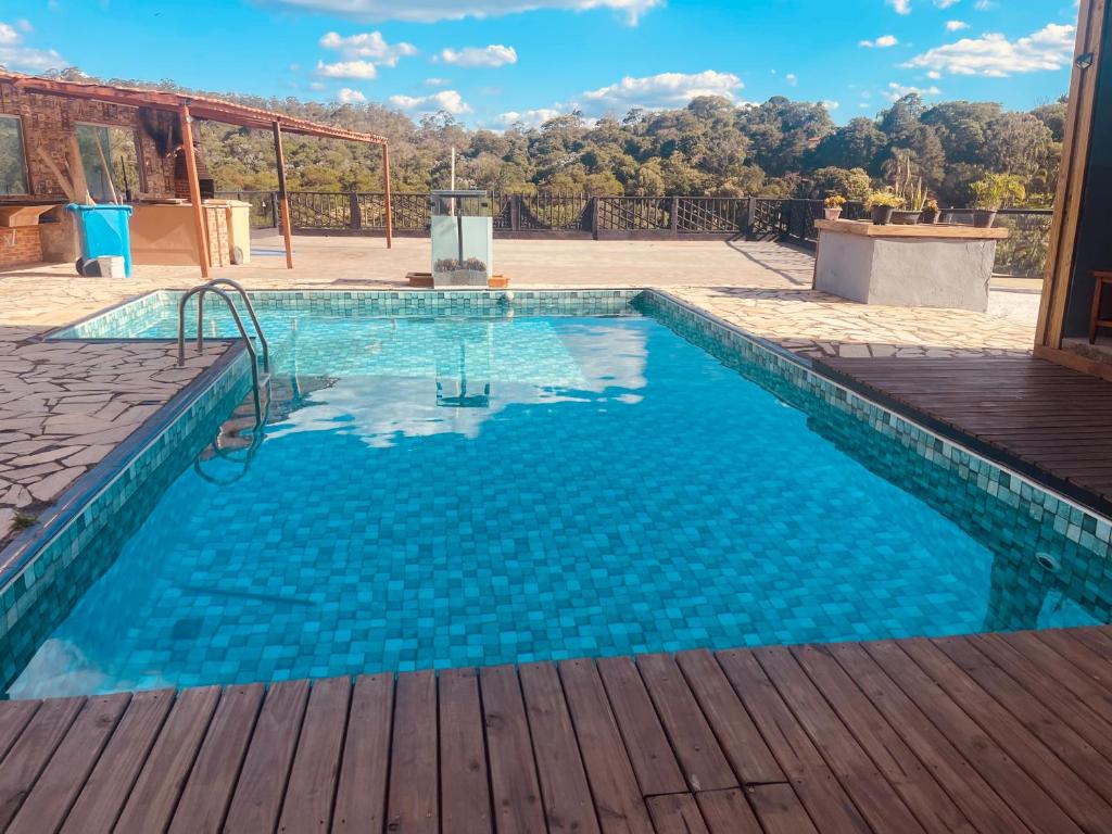 a large swimming pool with a wooden deck at Chácara Com Piscina e Vista das Montanhas in Atibaia