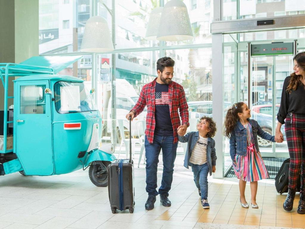 Una familia caminando por un centro comercial con un scooter. en Ibis Abdelmoumen Casa Centre, en Casablanca