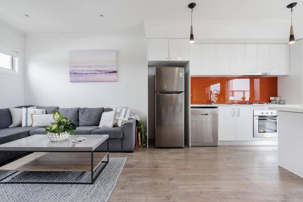a living room with a gray couch and a kitchen at Hide and Sea in Seaford