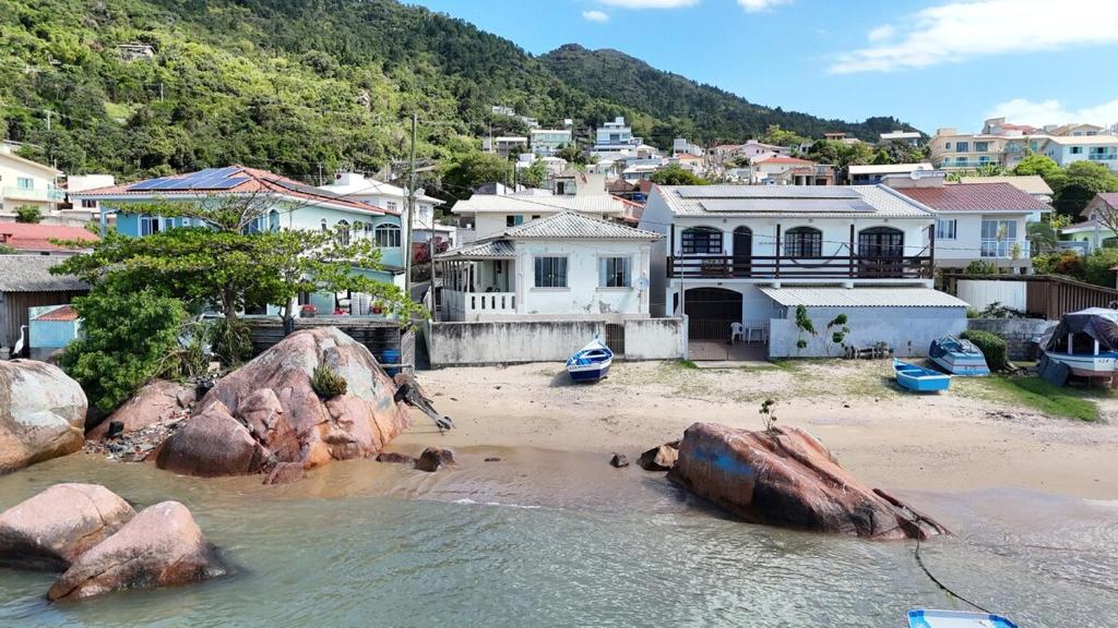 una spiaggia con rocce e case in una città di Recanto pé na areia a Governador Celso Ramos