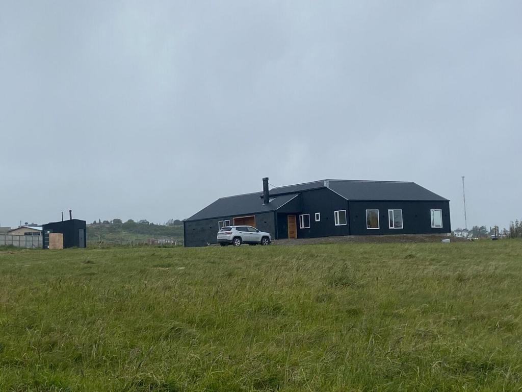 LeñaduraHermosa Casa con vista al Estrecho de Magallanes的一栋黑色的房子，一辆货车停在田野里