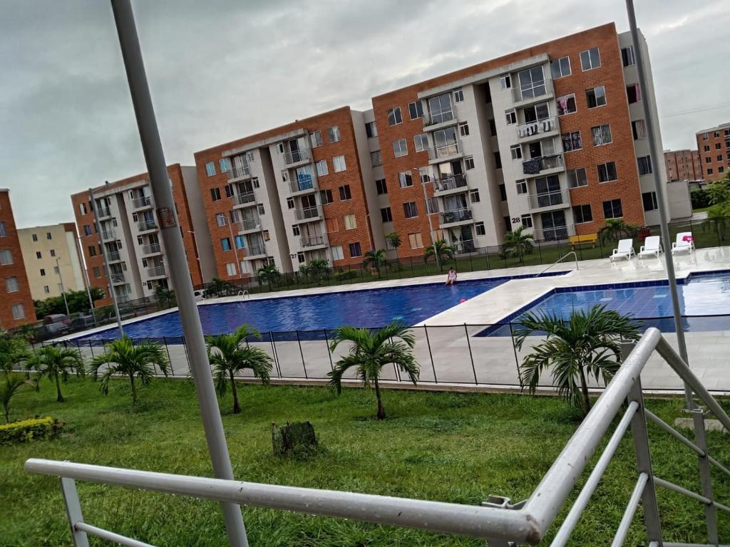 a swimming pool with palm trees and buildings at Apartamento Vacacional con Piscina in Ibagué