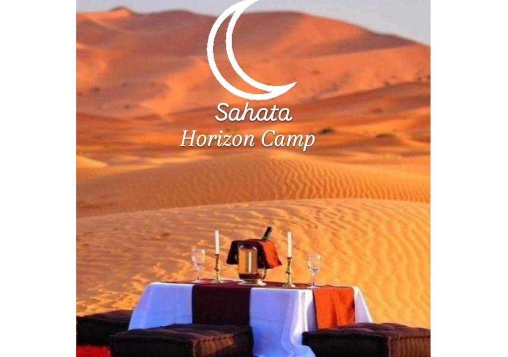 a table in the middle of a desert with a crescent moon at Sahara horizon Camp in Merzouga