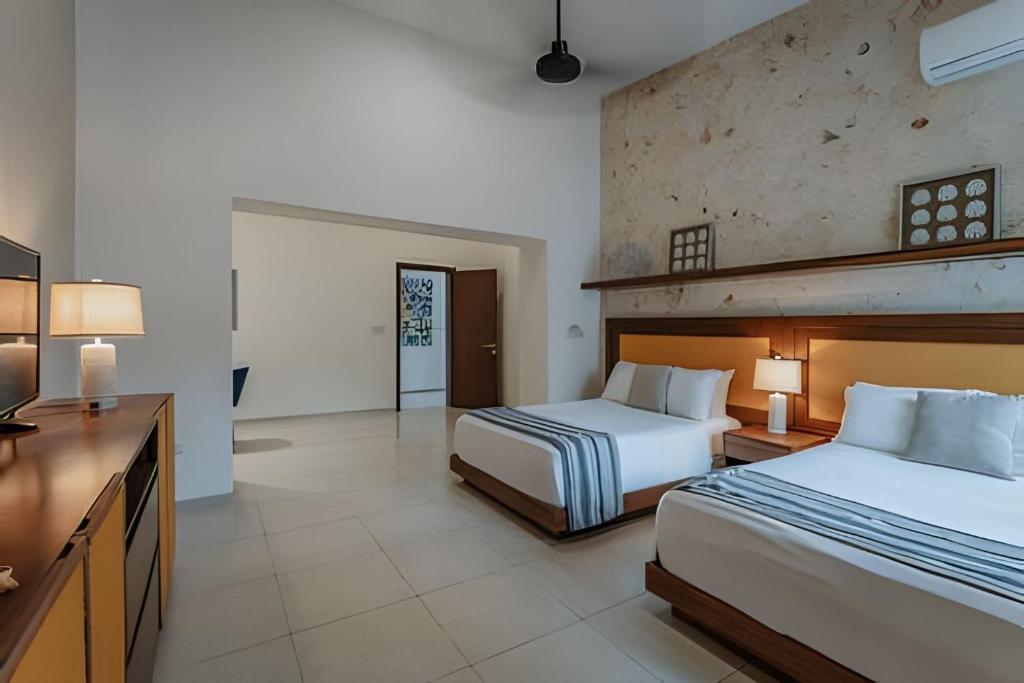 a hotel room with two beds and a television at Espectacular casa en Progreso con alberca in Progreso