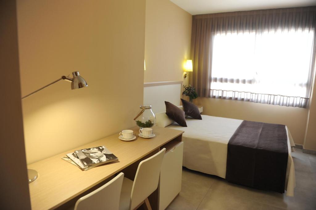 Habitación de hotel con cama, escritorio, mesa y sillas en La City Mercado, en Alicante