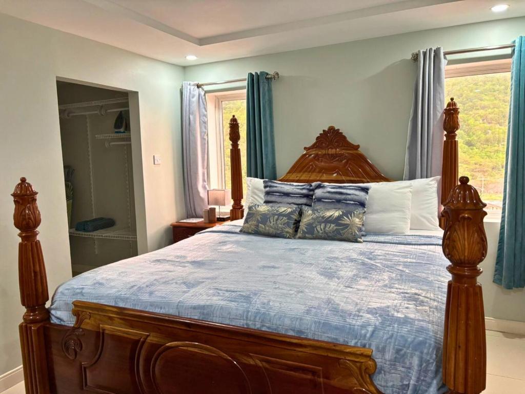 1 dormitorio con cama de madera y cortinas azules en CASA PORS Beach Front Apartment with security, pool &jacuzzi, en Portmore