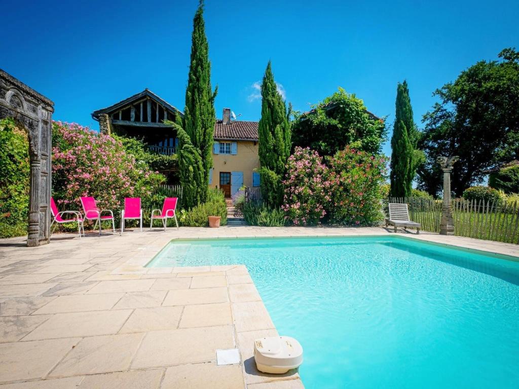 a swimming pool with pink chairs and a house at Beautiful farmhouse with private pool in Le Houga
