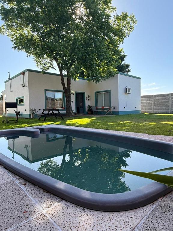 una piscina di fronte a una casa con un albero di Casona alegre con pileta y patio a San Pedro