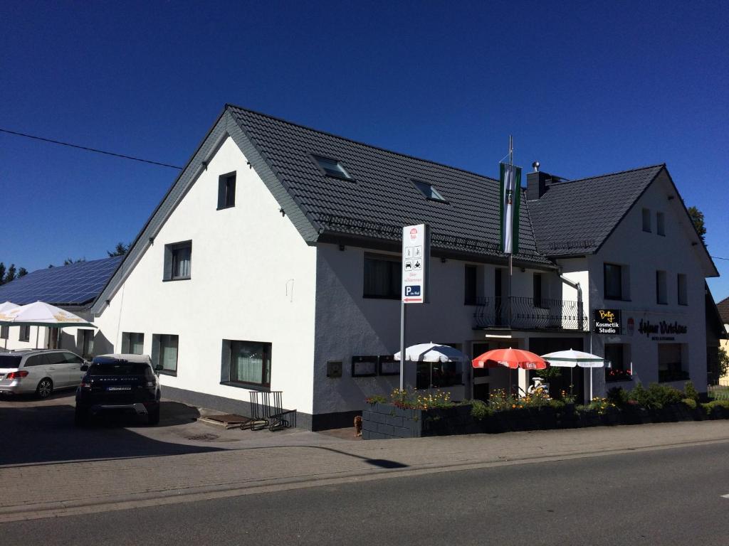 ein weißes Gebäude mit Sonnenschirmen davor in der Unterkunft Höfener Wirtshaus in Monschau