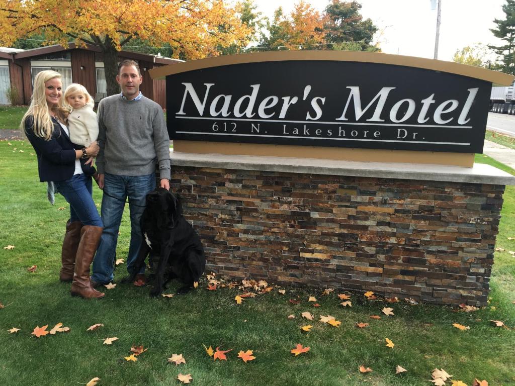 Eine Familie, die vor einem Schild mit einem Hund posiert. in der Unterkunft Nader's Motel & Suites in Ludington