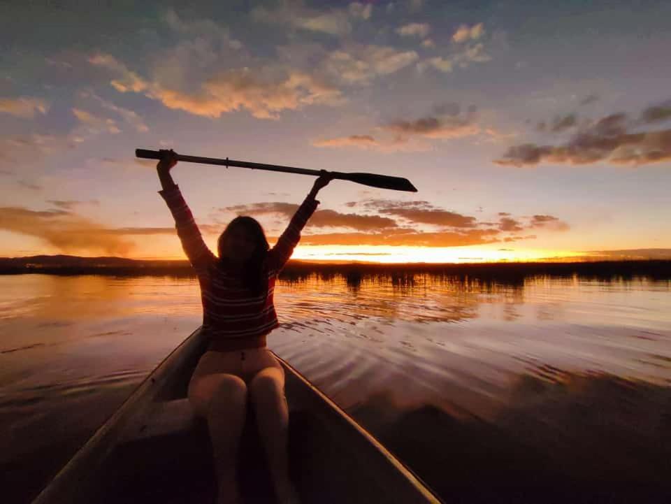 普诺Titicaca Lodge uros的日落时分，一位女子划着独木舟在水面上。