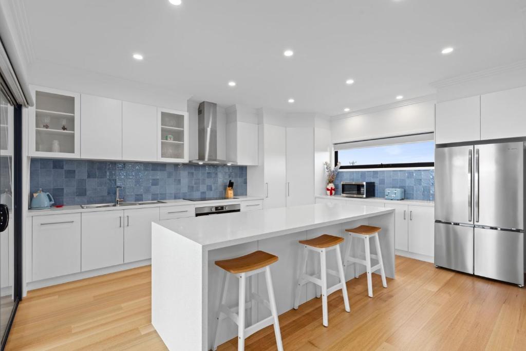 een witte keuken met witte kasten en barkrukken bij Mercer on Port in Portarlington