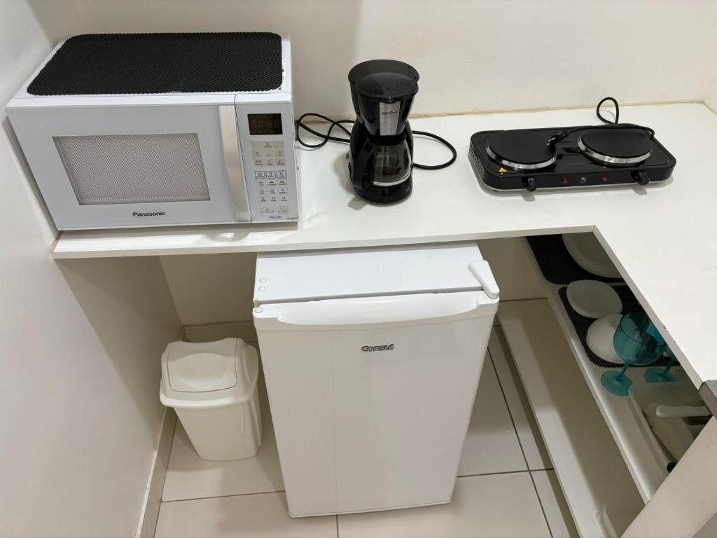 a kitchen counter with a microwave and a trash can at refugio pe na areia in Rio de Janeiro