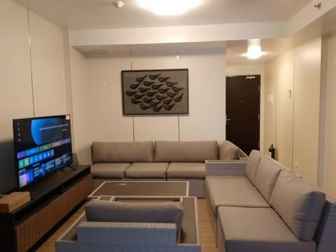 a living room with a couch and a flat screen tv at Luntian Luxury Condo in Tagaytay in Iruhin