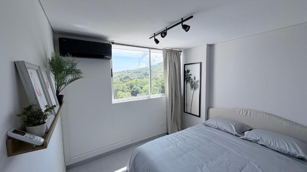 a white bedroom with a bed and a window at Citadela Di Sole Tropical Escape in Santa Fe de Antioquia