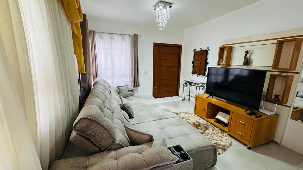Una sala de estar con un sofá y un televisor de pantalla plana. en Casa c Piscina Gigante, Lareira e Churrasqueira, en Campo Bom