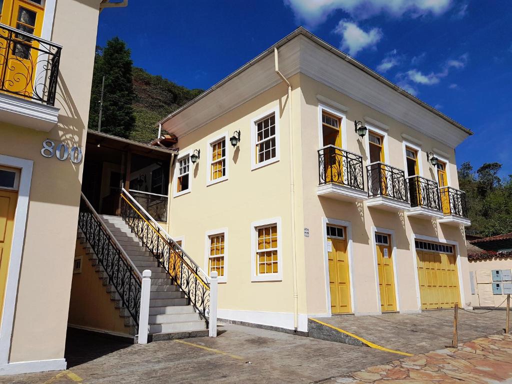 a large white building with yellow doors and stairs at Imperial Cidade Smart Suítes in Ouro Preto