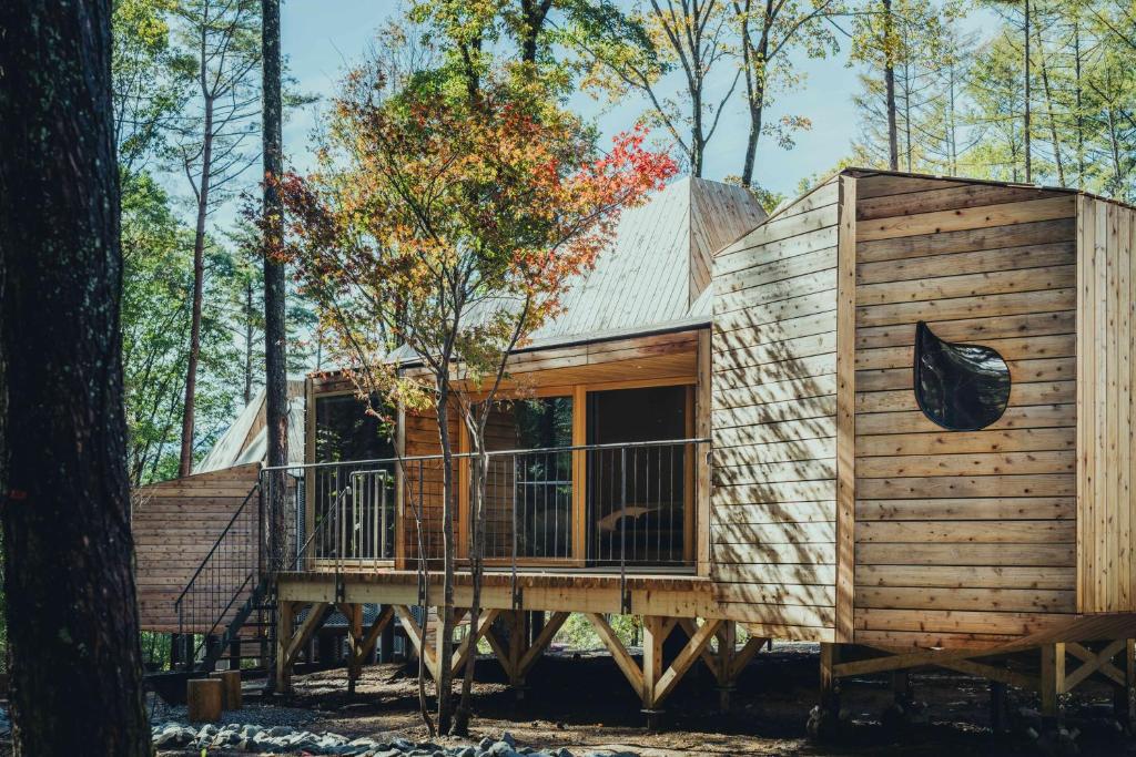 a wooden cabin in the woods with a balcony at SANU 2nd Home Minami-Alps 1st in Wada