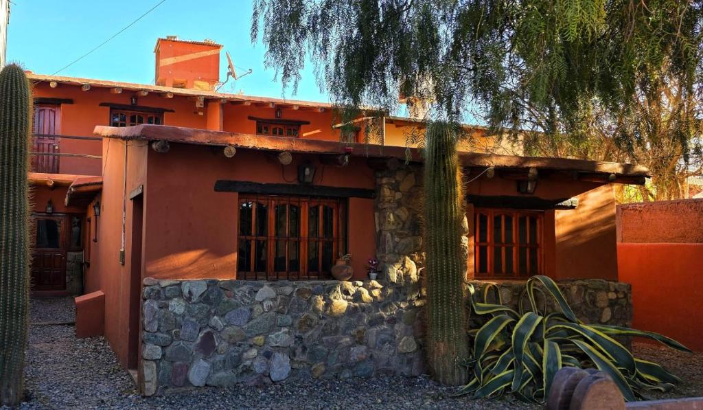 uma casa laranja com uma árvore em frente em Tierra Norte - Cabañas em Tilcara