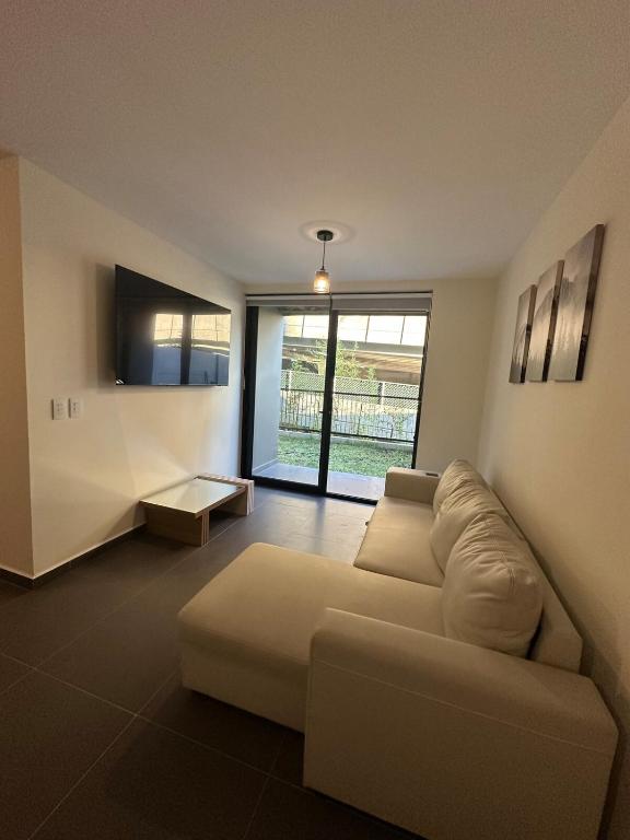 a living room with a couch and a tv at NU Lomas Garden in Antiguo Cuscatlán